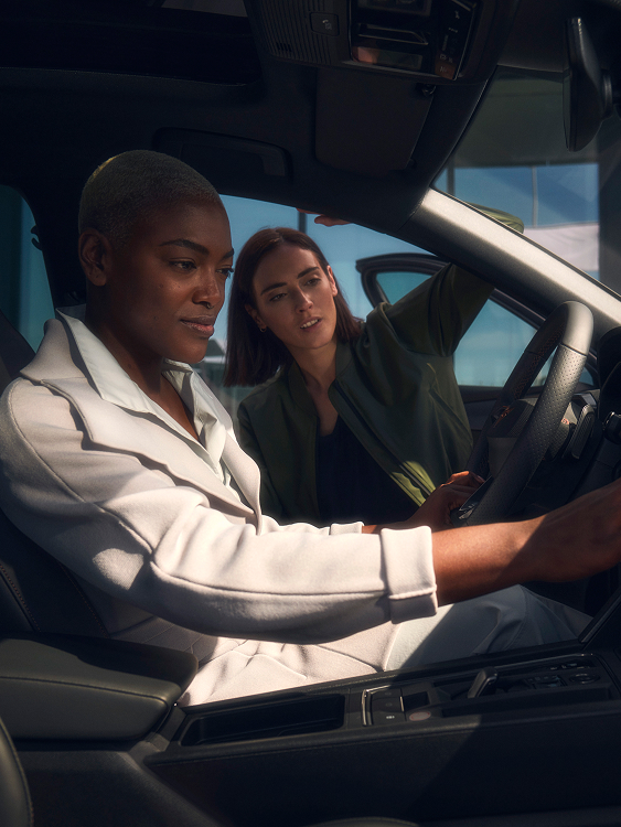 Zwei Personen im CUPRA Innenraum eine Person greift zum Infotainment Display